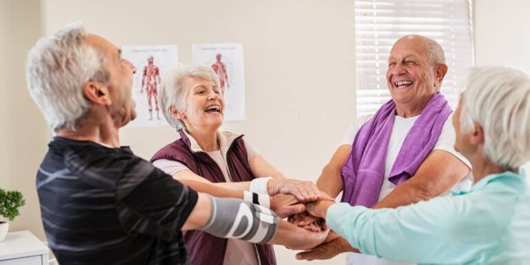 Elderly Group Joining Hands After Therapy at Assisted Living Facility