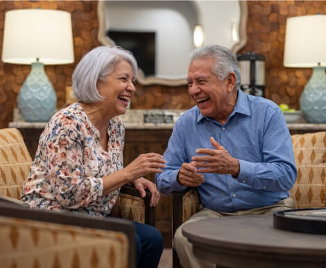 Elderly Couple Laughing Together in Common Lounge at Assisted Living Facility Elderly Couple Laughing Together in Common Lounge at Assisted Living Facility