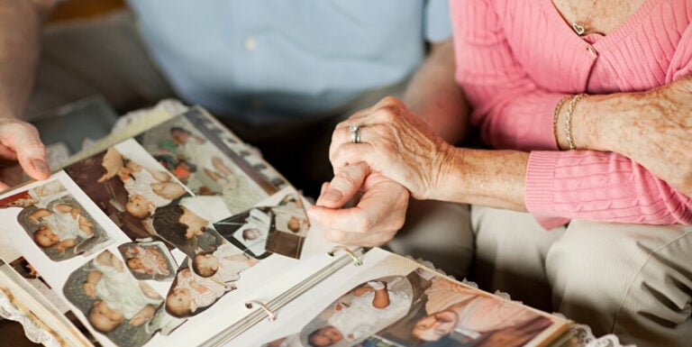 Elderly Couple Looking through Old Family Photo Albums Together at Memory Care Facility