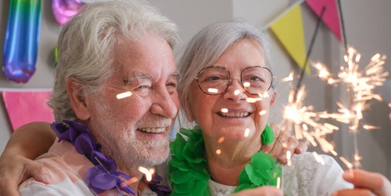 Joyful Elderly Couple Celebrating with Sparklers and Party Decorations at Memory Care Facility
